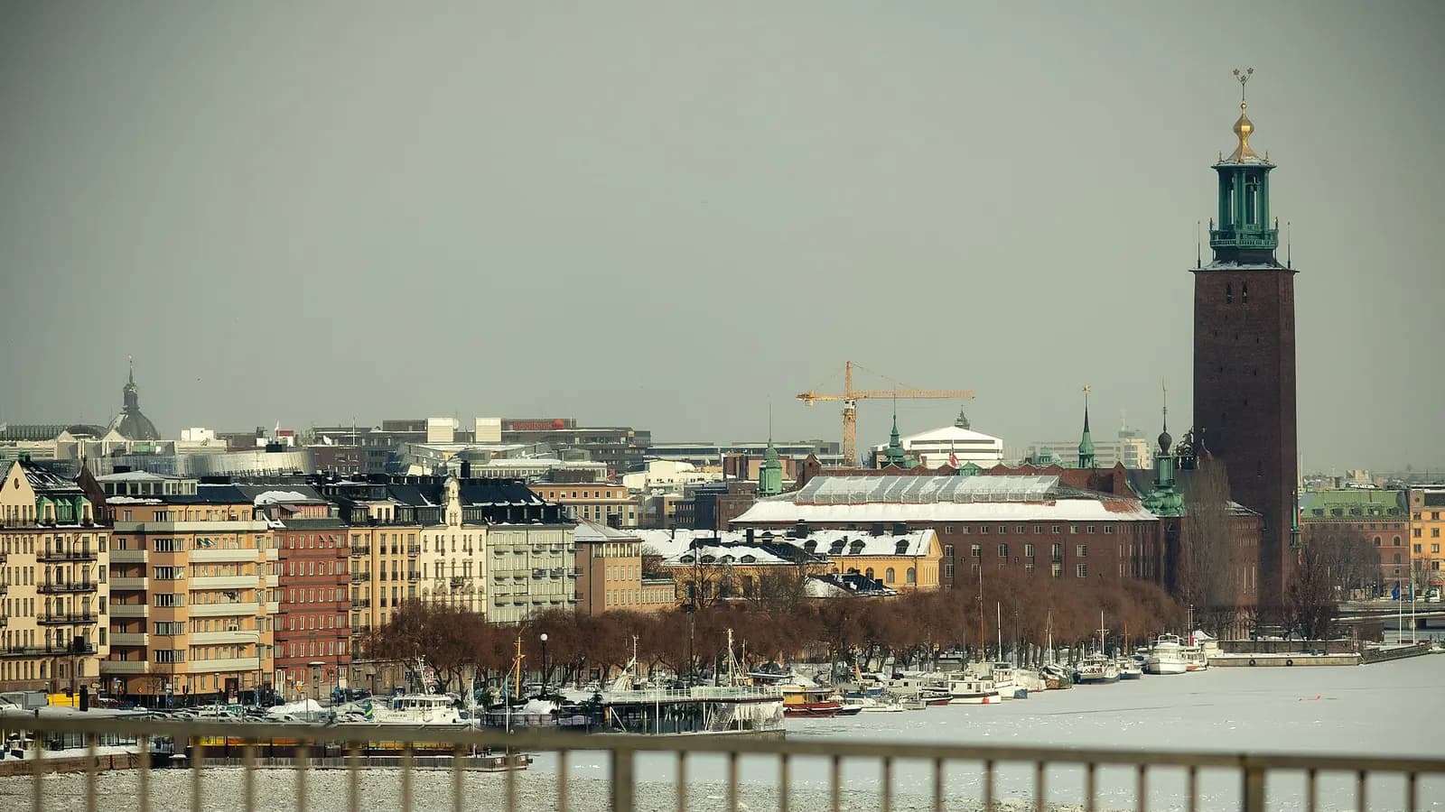 Flerbostadshus på Kungsholmen och Stockholms stadshus en vinterdag, sett över det isbelagda vattnet